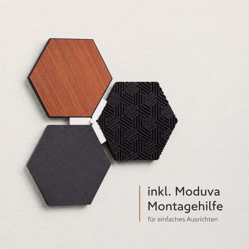 May include: Three hexagonal wall tiles in a modern design. One tile is wood-grained, another is textured black, and the third is a geometric black pattern. The tiles are connected with white connectors. Text in the image reads "inkl. Moduva Montagehilfe f&uuml;r einfaches Ausrichten."