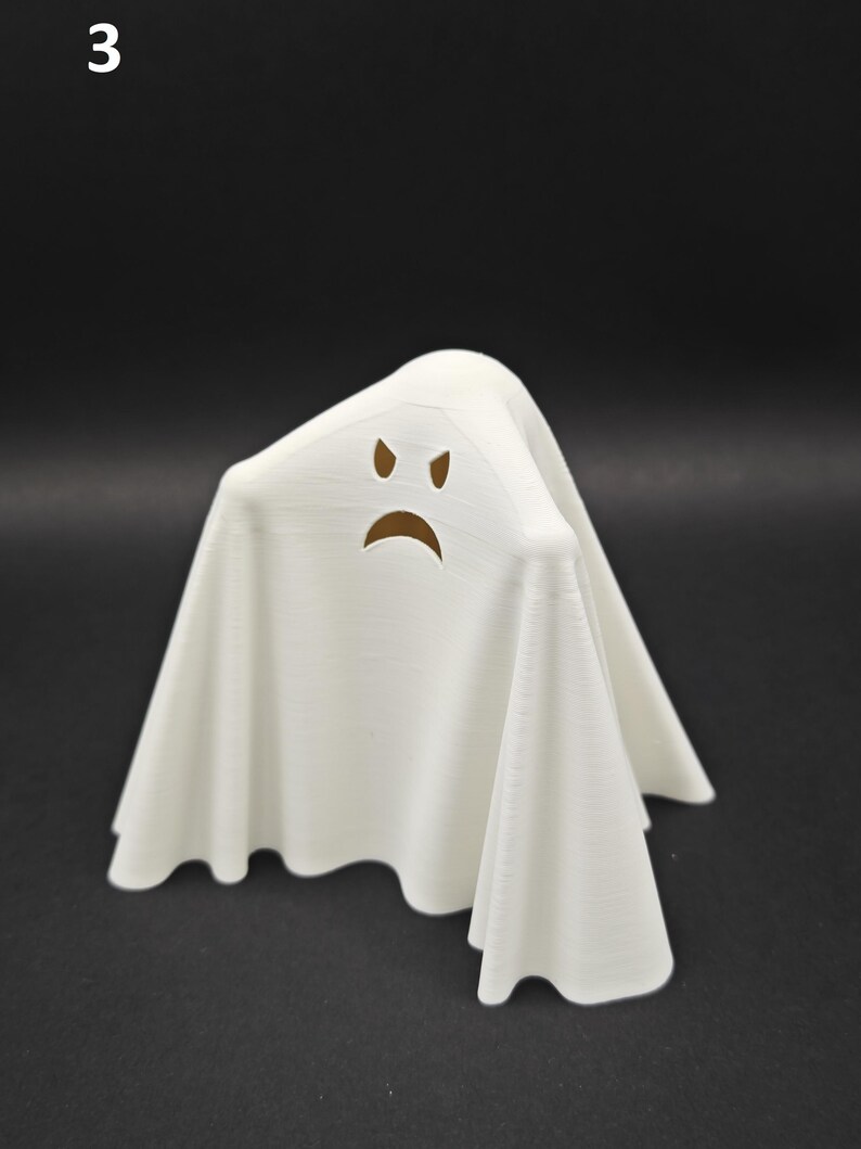 Puede incluir: Figurita de fantasma blanco con una cara fruncida, hecha de pl&aacute;stico impreso en 3D.