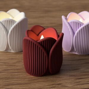 May include: Three tulip-shaped candle holders in white, burgundy, and lavender. Each holder has vertical lines and holds a glowing candle. The holders are arranged on a wooden surface, creating a warm and inviting ambiance.