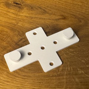 May include: White plastic cross-shaped bracket with five holes and two round knobs.