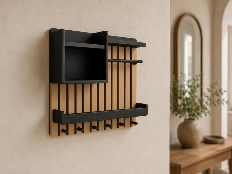 May include: A wall-mounted organizer featuring a light wood slatted back panel with a black storage box, a horizontal bar, a shelf, and seven black hooks along the bottom edge. The unit combines natural wood tones with matte black metal components.