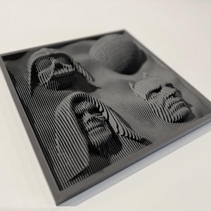 May include: A gray framed wall art piece with a 3D design of four faces. The faces are made of layered lines and appear to be from a science fiction movie.