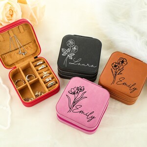 Puede incluir: Cuatro pequeñas cajas cuadradas de joyería con diseños florales y nombres personalizados. Las cajas son de color rojo, negro, rosa y marrón.