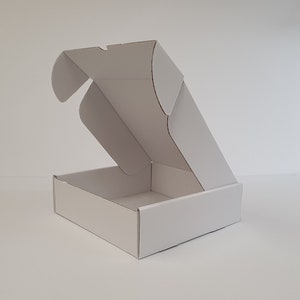May include: A white cardboard box with the top flap open. The box is empty and ready to be filled.