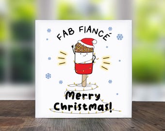 May include: A white Christmas card with a cartoon popsicle wearing a Santa hat and wrapped in Christmas lights. The text reads "FAB FIANCÉ" and "Merry Christmas!" with snowflakes.