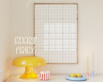 May include: A white table with a yellow lamp, a red and white striped mug, and a blue bowl with two yellow lemons. There is a wooden frame on the wall behind the table. The text "MOCKUP FRAME" is written on the wall.