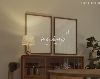 May include: Two wooden picture frames with a brown finish, one with a blank white space and the other with a blurry image of trees. The frames are hanging on a wall above a wooden cabinet with glass doors and drawers. A table lamp with a cream-colored shade sits on the cabinet. A small bonsai tree is in a pot on the right side of the image.