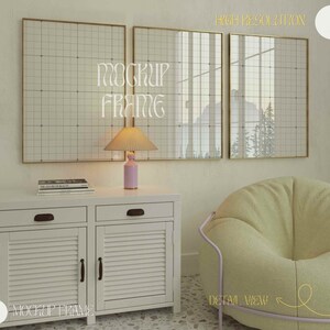 May include: Three framed wall art pieces with a grid pattern hang above a white cabinet. A pink lamp with a pleated shade sits on the cabinet, next to a stack of books. A light green beanbag chair and a gold-framed mirror are also visible.