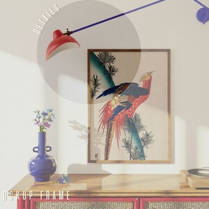 May include: A framed print of a colorful pheasant bird with a blue background. The print is hanging on a white wall above a wooden shelf with a vase of flowers and a record player.
