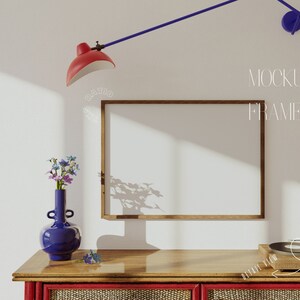 May include: A wooden frame mockup with a white background, a red lamp, a blue vase with flowers, and a record player on a wooden table with a red and brown striped front.