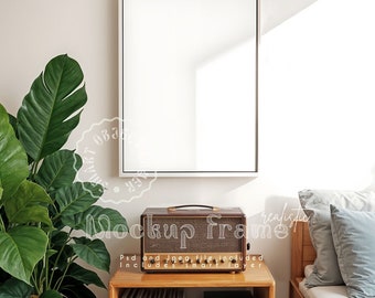 May include: A white framed canvas mockup hanging on a wall, above a wooden cabinet. A vintage-style amplifier sits on the cabinet, with a large green plant to the left. The text on the image says "Mockup Frame".