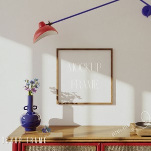 May include: A wooden picture frame with a white background and the text "MOCKUP FRAME" in white. The frame is on a wooden shelf with a blue vase with flowers and a record player.
