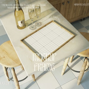 Può includere: Un mockup incorniciato bianco con un motivo a griglia all'interno della cornice. La cornice è appoggiata su un tavolo bianco con due sgabelli in legno. Una bottiglia di champagne e due bicchieri da champagne sono sul tavolo.