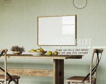 May include: A wooden table with two chairs and a framed picture hanging on a green wall. The table has a bowl of pears on it. The text "MOCKUP FRAME SEM DESIGN STUDIO" is visible below the picture.
