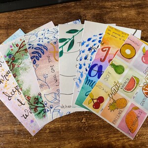May include: A set of eight watercolour cards with floral and fruit illustrations. The cards feature handwritten text, including the words "When you sleep I will give you" and "The Fruits of the Spirit".