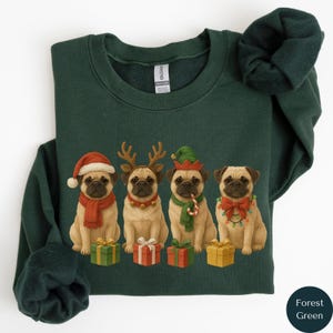Op de afbeelding: Bostgroen sweatshirt met een feestelijk ontwerp van vier mopshonden in kerstoutfits. Elke mopshond draagt een ander accessoire, waaronder een kerstmuts, rendiergewei, een elfenmuts en lichtslingers. Elke mopshond zit voor een ingepakt cadeau.