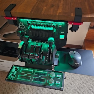 May include: A black flight simulator control panel with green LED lighting, mounted under a wooden surface. Features include levers, switches, and a throttle quadrant. A Logitech mouse and mousepad are visible.