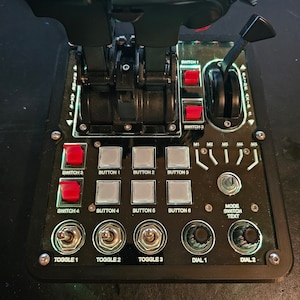 Könnte beinhalten: Ein schwarzes Bedienfeld mit mehreren Knöpfen, Schaltern, Kippschaltern und Drehknöpfen. Das Panel ist mit "Switch 1", "Switch 2", "Switch 3", "Switch 4", "Button 1", "Button 2", "Button 3", "Button 4", "Button 5", "Button 6", "Toggle 1", "Toggle 2", "Toggle 3", "Dial 1", "Dial 2" und "Mode Switch Text" beschriftet.