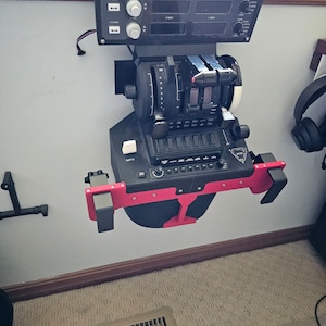 May include: Black and red flight simulator control panel mounted on a wall. The panel features various dials, switches, and levers, with a digital display. The unit is designed for flight simulation and training purposes.