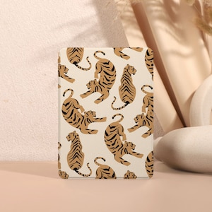 Op de afbeelding: Een witte telefoonhoes met een herhalend patroon van bruine en zwarte tijgers. De tijgers zijn in verschillende poses, sommige zitten, sommige liggen en sommige staan.