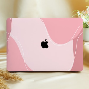 Puede incluir: Piel de portátil rosa con un diseño abstracto de líneas blancas y formas rosas. El logotipo de Apple es visible en el portátil.