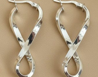 May include: A pair of silver-toned hoop earrings featuring a twisted, infinity-style design. Each earring has a smooth, reflective metallic surface and a hinged post closure at the top, forming a continuous, elongated loop shape with a central twist.
