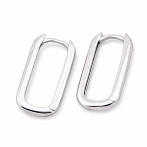 May include: A pair of silver-colored, rectangular hoop earrings. The earrings have a smooth, polished finish and a simple, modern design. The hoops are approximately 1 inch in length and 0.5 inches in width.