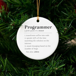 May include: White ceramic Christmas ornament with the word "Programmer" defined as someone who transforms coffee into code, spends 95% of their time searching for solutions online, and whose mood changes based on the number of bugs. The ornament also says "See also: John".