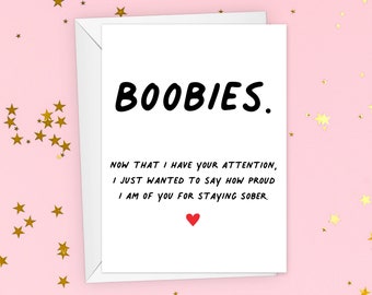 May include: A white card with black text that reads "BOOBIES. NOW THAT I HAVE YOUR ATTENTION, I JUST WANTED TO SAY HOW PROUD I AM OF YOU FOR STAYING SOBER." A red heart is at the bottom of the card.