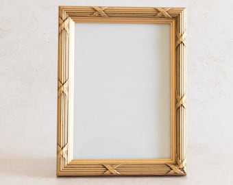 May include: A gold picture frame with a decorative, ornate design. The frame is empty and ready for a photo or artwork.