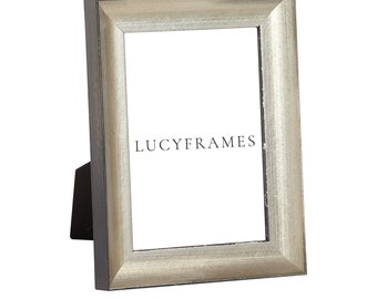 May include: A silver picture frame with a black mat and a wood stand. The frame has a distressed look and the text "LUCYFRAMES" is printed on the mat.