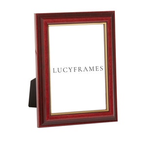 May include: A red wood picture frame with a gold trim. The frame has a white mat and the text "LUCYFRAMES" is printed on the mat.