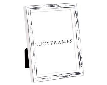 May include: White picture frame with a distressed black finish. The frame is standing upright on a white surface. The text "LUCYFRAMES" is printed on the frame.