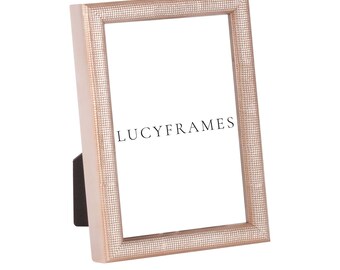 May include: A rose gold picture frame with a textured surface. The frame is made of wood and has a simple design. The frame is 4x6 inches in size. The frame is made by Lucy Frames.