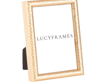 May include: A gold hammered picture frame with a white mat and the text "LUCYFRAMES" printed on the mat.
