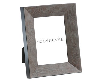 May include: A gray wood picture frame with a black border. The frame is standing on a white surface. The text "LUCYFRAMES" is printed on the frame.