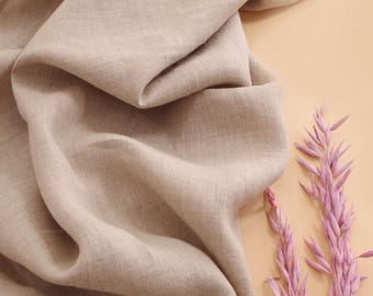 Könnte beinhalten: Nahaufnahme eines beigefarbenen Leinenstoffs mit weicher, strukturierter Oberfläche. Der Stoff ist drapiert und gefaltet und erzeugt einen natürlichen, fließenden Look.