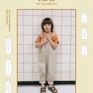Puede incluir: Un niño con un peto beige y una camiseta naranja, de pie frente a una pared de azulejos. La imagen incluye el texto "KAI DUNGAREES" y "SEWING PATTERN 16 VARIANTS". El peto tiene un corte holgado y cómodo.