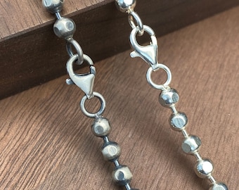 May include: Two silver chains with round links. One chain has a smooth finish, while the other has a textured finish.
