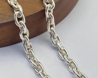 May include: Two silver chains with a rope design. The chains are laid out on a wooden surface.