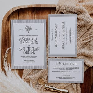 May include: A set of wedding stationery, including an invitation, rehearsal dinner card, and details card. The cards have a white background with a striped border and black text. The main invitation announces the wedding of Rebecca Thompson and Nicholas Greene.