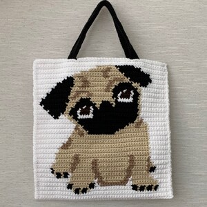 May include: White crocheted tote bag with a brown and black pug design. The pug is sitting with its front paws forward and its head tilted slightly to the side. The bag has black handles.