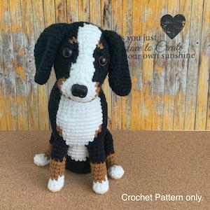 Può includere: Schema di uncinetto per un amigurumi di cane da montagna bernese. Il cane è seduto con le zampe incrociate e ha uno schema di colori nero, bianco e marrone. Lo schema è solo per l'uncinetto.