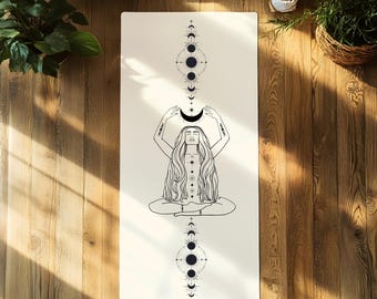 May include: White yoga mat with a black and white illustration of a woman in a yoga pose with her arms raised above her head, holding a crescent moon. The illustration is surrounded by a pattern of moons and stars.