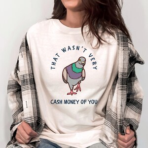 May include: A white t-shirt with a cartoon pigeon and the text "That wasn't very cash money of you".