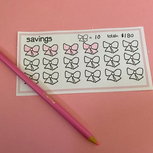 May include: A white sheet with the word "savings" printed in black. There are 18 pink and white bow stickers on the sheet. The text "10 = total = $180" is printed in black at the top of the sheet.