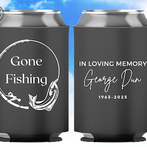 May include: Black can cooler with white text and graphics. One side reads "Gone Fishing" with a fishing rod and fish graphic. The other side reads "In Loving Memory George Dun 1963-2023".