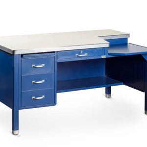 May include: A blue metal desk with a white top and silver trim. The desk has three drawers on the left side and a single drawer in the middle. It also features a side extension. The desk is a classic design.