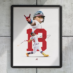 May include: A framed print featuring a baseball player in action, with the number 13 in red. The player is wearing a white uniform with red and yellow accents. The image includes a signature and the Atlanta Braves logo.