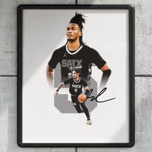 May include: Framed print featuring a basketball player in a black uniform with the text "SATX" and the number 5. The image has a grayscale background with a signature in the lower right corner. The player is holding a basketball.
